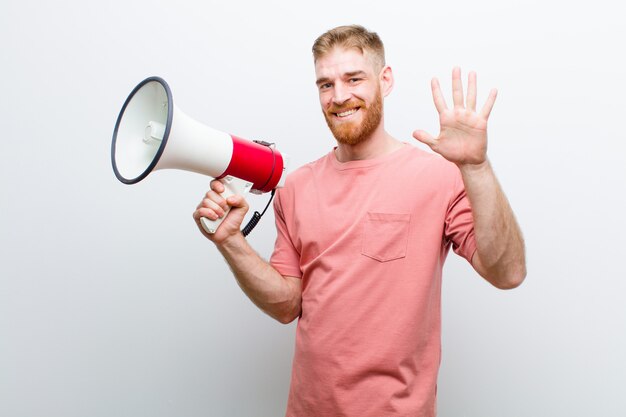 Young red head man with a megaphone against white