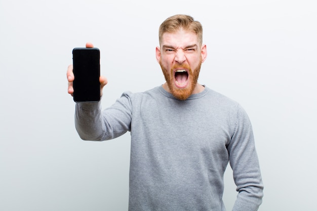 Young red head man with a smart phone against white background