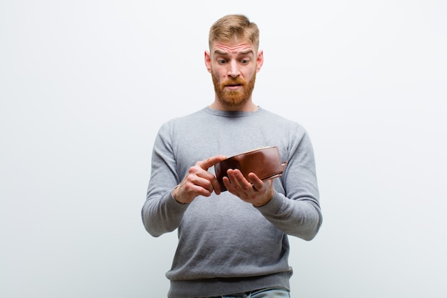 Young red head man with a wallet against white background