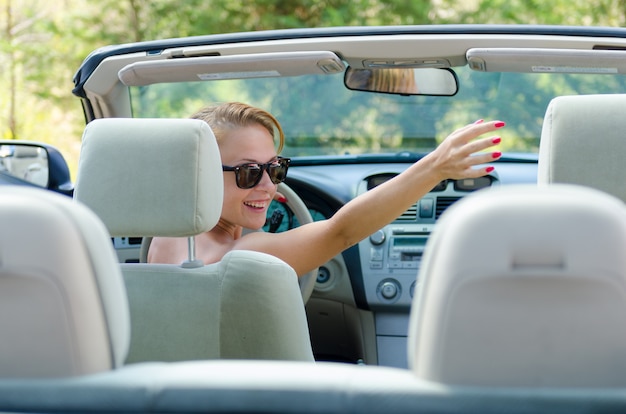 運転中に彼女の友人に挨拶する若い赤い女性