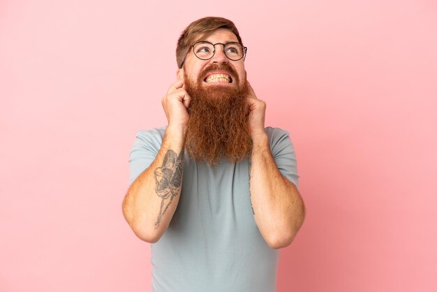 Photo young reddish caucasian man isolated on pink background frustrated and covering ears