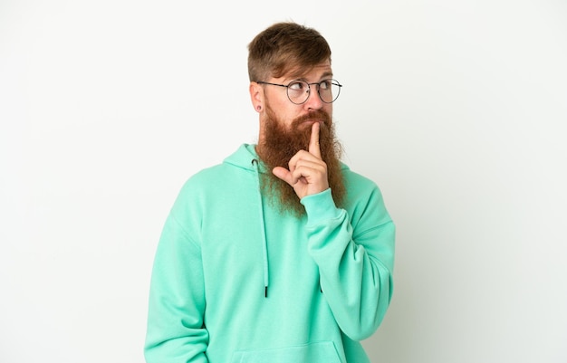 Young reddish caucasian man isolated on white background showing a sign of silence gesture putting finger in mouth