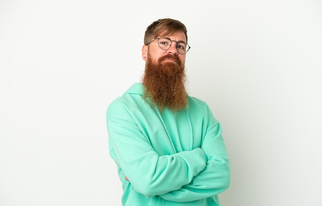 Young reddish caucasian man isolated on white background with arms crossed and looking forward