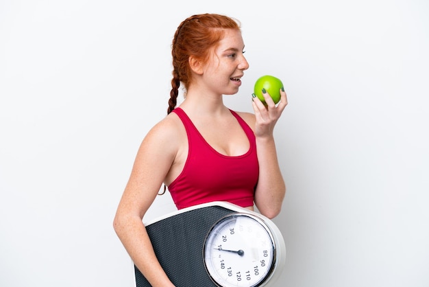 Молодая красноватая женщина на белом фоне с весами и яблоком