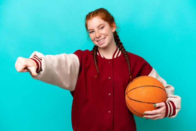 엄지손가락 제스처를 주는 파란색 배경에 고립 농구를 하는 젊은 붉은 여자