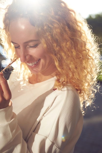 Young redgead curly hairstyle smiling woman close up portrait in sunlight