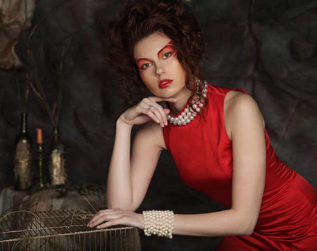 Young redhair woman with creative visage wearing red dress