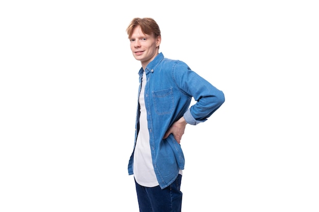 Young redhaired guy in a blue denim shirt on a background with copy space