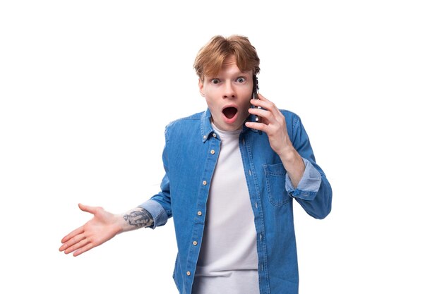 Photo young redhaired guy indignantly listens attentively to the interlocutor on the phone