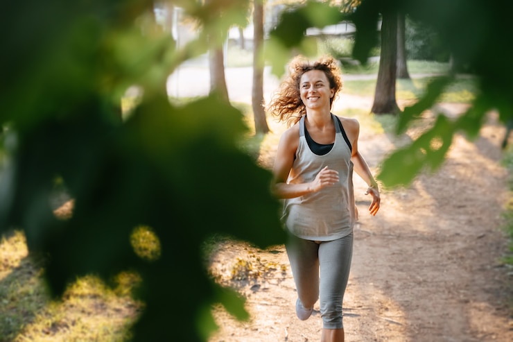 Photo young redhaired woman runs a marathon outdoors in a city park in the forest warm rays of the sun