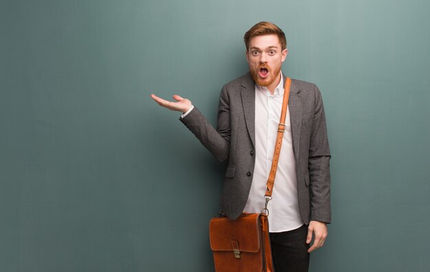 Young redhead business man holding something on palm hand