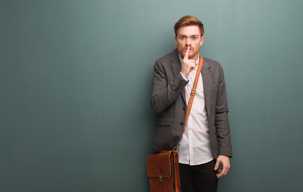 Young redhead business man keeping a secret or asking for silence