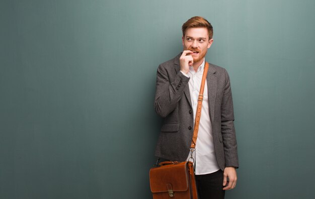 Young redhead business man relaxed thinking about something looking at a copy space