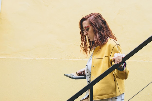 young redhead business woman entrepreneur in casual clothes outside walking down the stairs