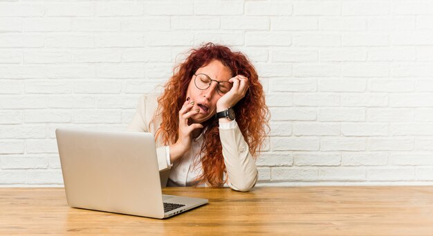 Young redhead curly woman working with her laptop whining and crying disconsolately.