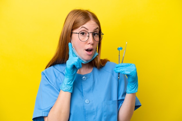 Young redhead dentist woman isolated on yellow background intending to realizes the solution while lifting a finger up