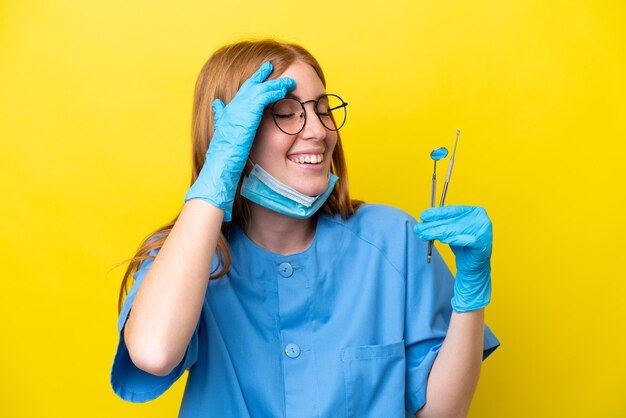 Young redhead dentist woman isolated on yellow background smiling a lot