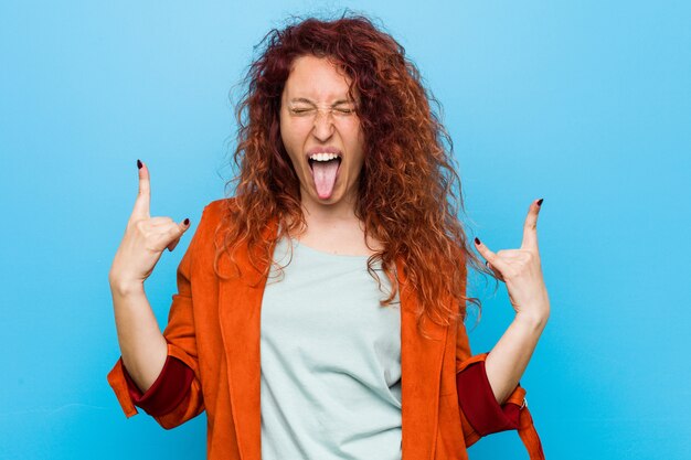 Young redhead elegant woman showing rock gesture with fingers