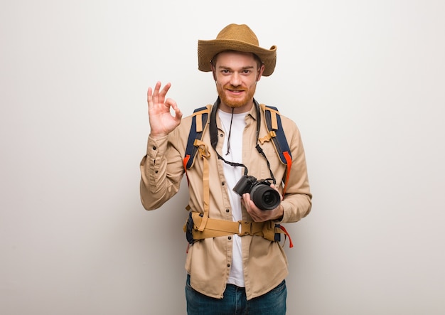 Young redhead explorer man cheerful and confident doing ok gesture.