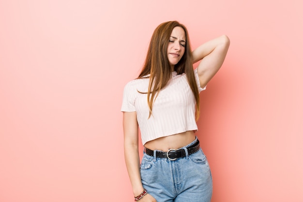 Young redhead ginger woman against a pink wall suffering neck pain due to sedentary lifestyle.