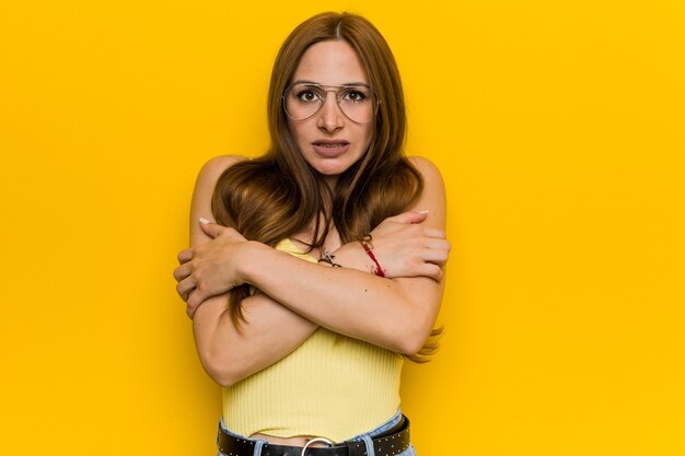 Young redhead ginger woman with freckles going cold due to low temperature or a sickness.