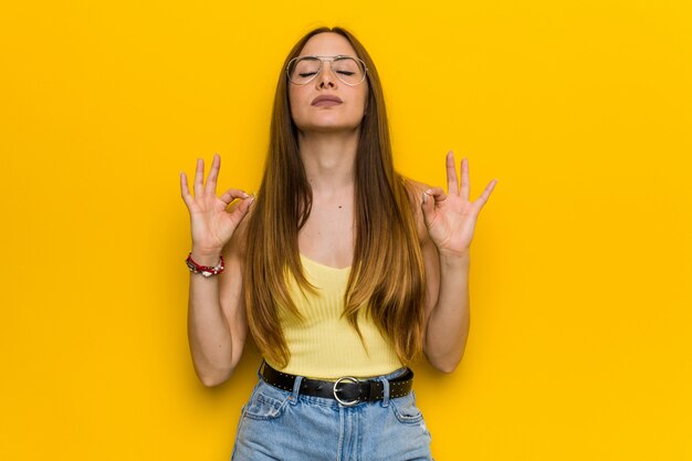 La giovane donna dello zenzero di redhead con freckless si rilassa dopo la dura giornata lavorativa, sta eseguendo l'yoga.