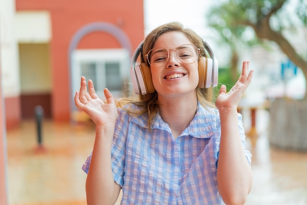 Young redhead girl headphones at outdoors smiling a lot