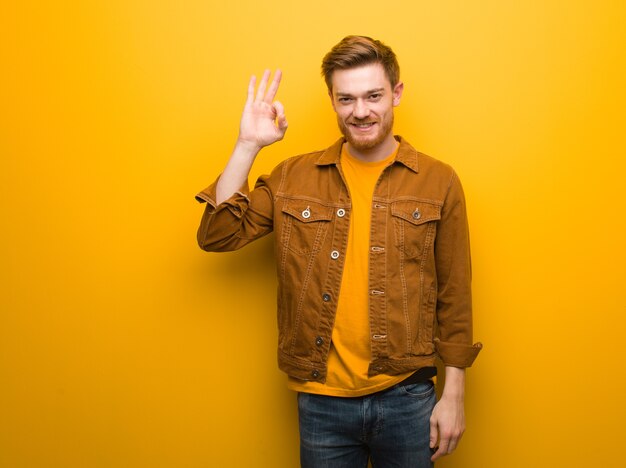 Young redhead man cheerful and confident doing ok gesture