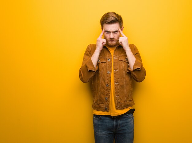 Young redhead man doing a concentration gesture