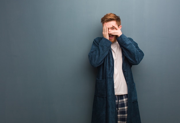 Young redhead man in pajama feels worried and scared