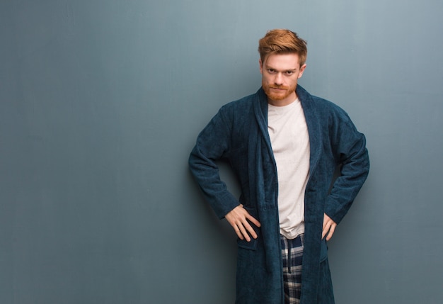 Young redhead man in pajama scolding someone very angry