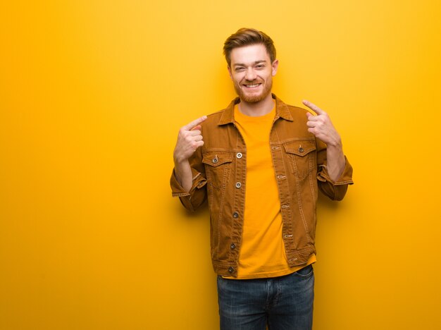 Young redhead man smiles, pointing mouth