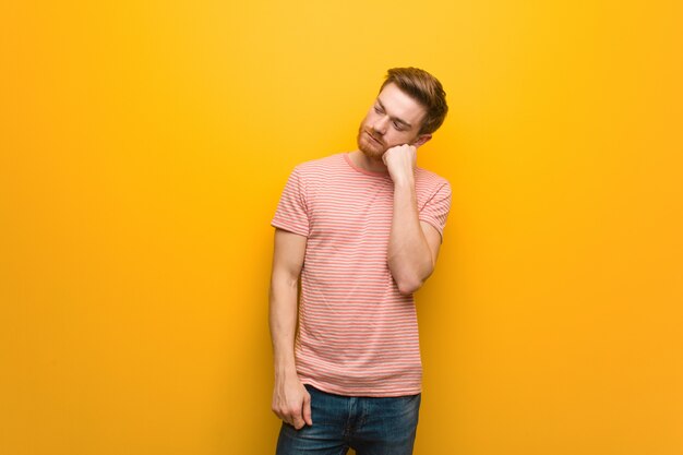 Young redhead man thinking of something, looking to the side