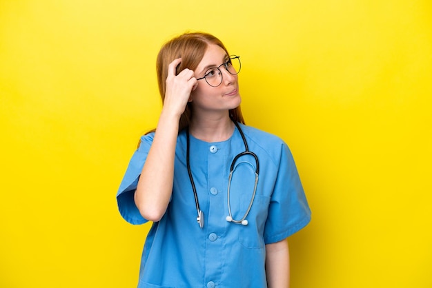 Young redhead nurse woman isolated on yellow background having doubts and with confuse face expression