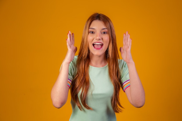 Young redhead shocked and surprised on yellow background.