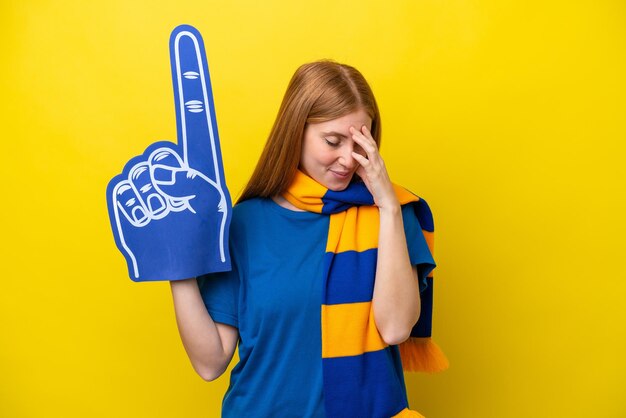 Young redhead sports fan woman isolated on yellow background laughing