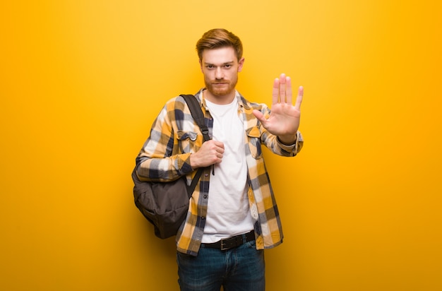 Uomo giovane studente di redhead mettendo mano davanti