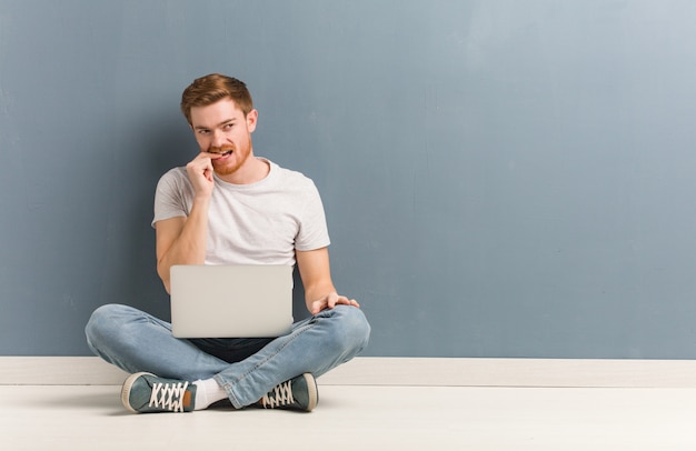 Young redhead student man sitting on the floor relaxed thinking about something