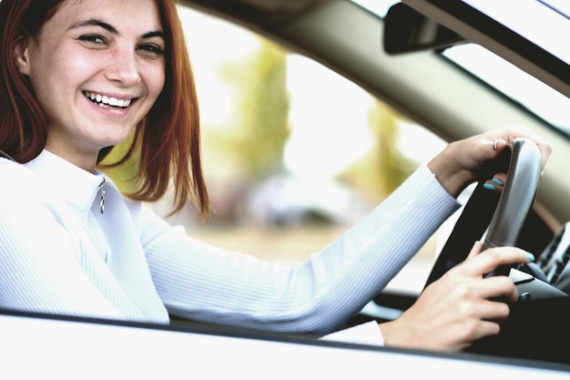 Young redhead woman driver in the car