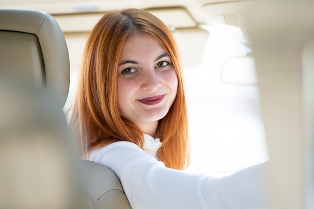 幸せそうに笑って車を運転して若い赤毛の女性ドライバー。