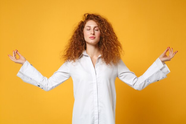 Young redhead woman girl in casual white shirt posing isolated on yellow orange wall