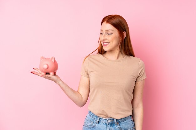 大きなpiggybankを保持している若い赤毛の女性