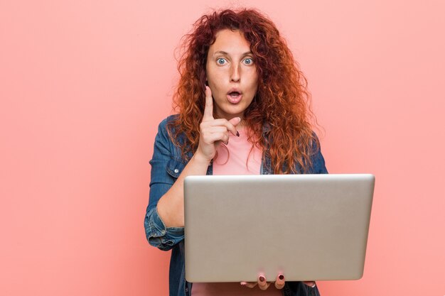 Young redhead woman holding a laptop having some great idea