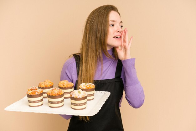 Young redhead woman holding a muffins tray cut out isolated