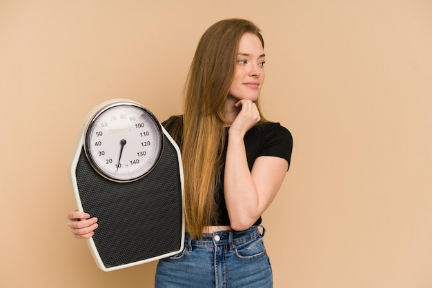 Young redhead woman holding a scale isolated cut out