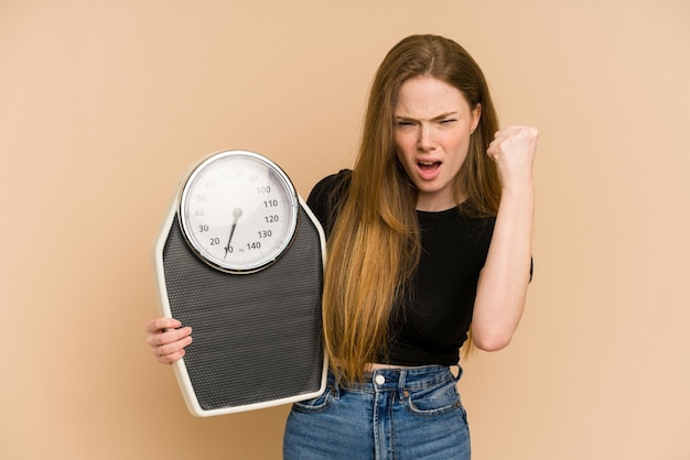 Young redhead woman holding a scale isolated cut out