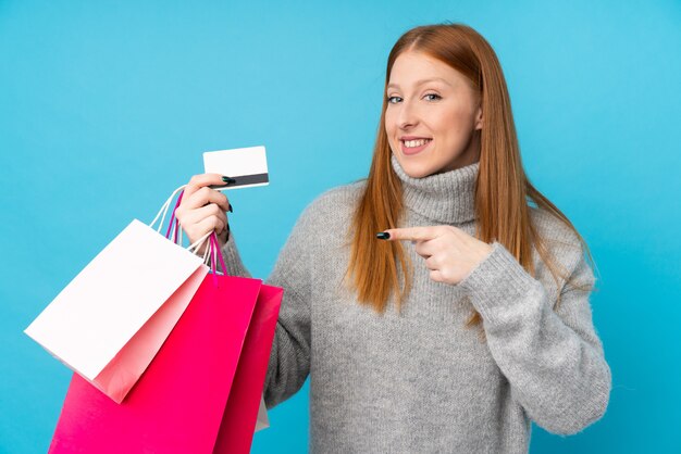 Photo young redhead woman holding shopping bags and a credit card