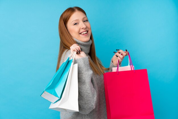 Young redhead woman holding shopping bags and smiling