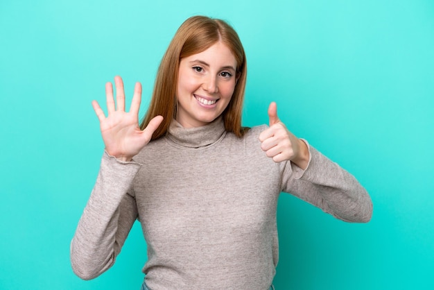 Young redhead woman isolated on blue background counting six with fingers