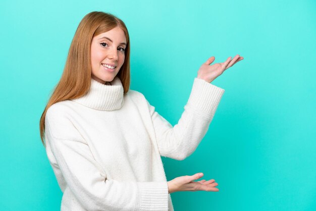 Young redhead woman isolated on blue background extending hands to the side for inviting to come